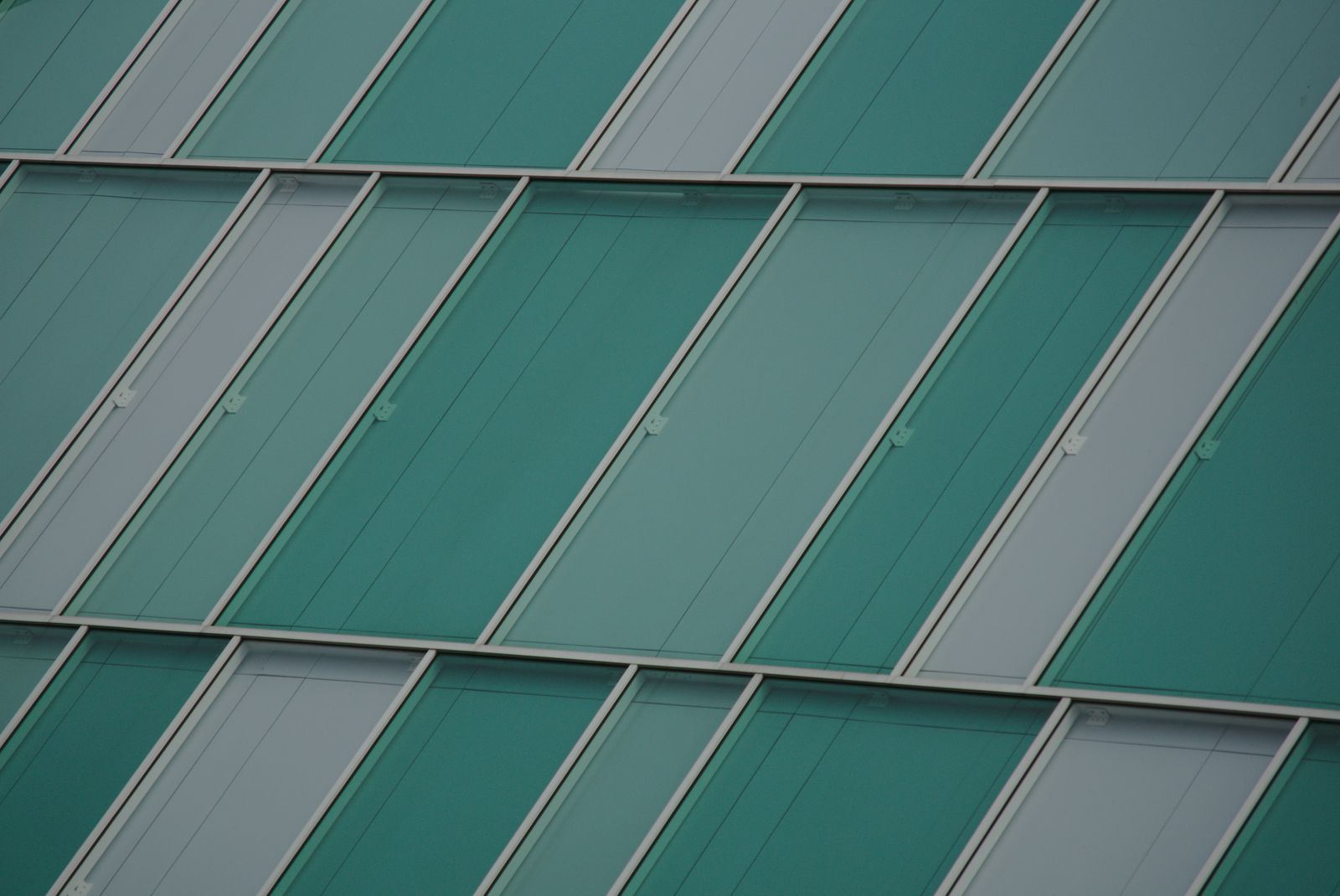 Intersecting lines of teal glass panels on a modern building facade.